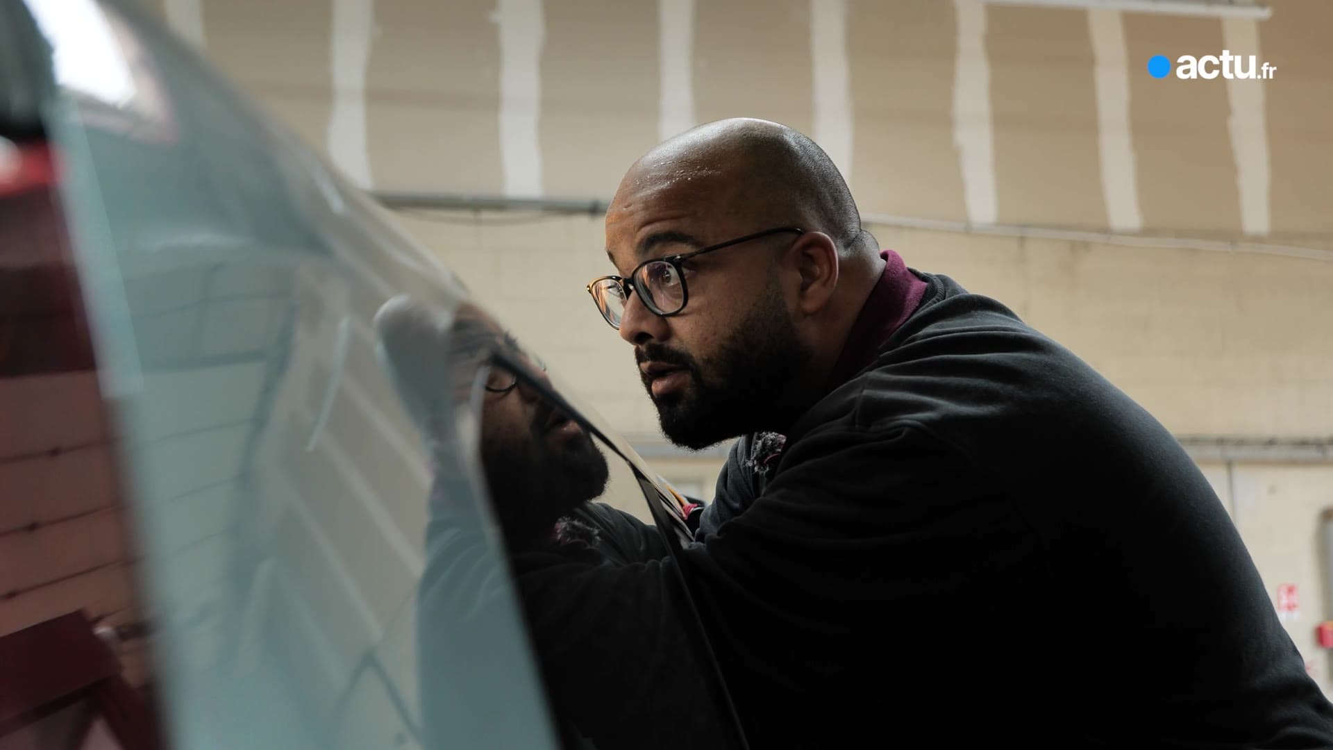 Amine, gérant d'ADE Débosselage, contrôle une carrosserie au reflet de la lampe
